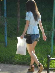 Street Candid of a Girl in Denim Mini-Shorts, Transparent Blouse on High Heels