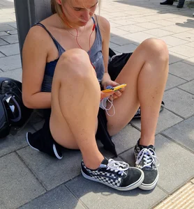 Candid girl in shorts sitting on the ground at the station street creepshot