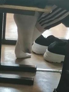 Teen college girl's feet in white socks under desk in class, photos and a video