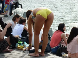 Cute Girl in Denim Shorts and Swimsuit Undressing on the Riverbank Candid Photo