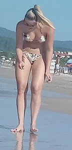 Smooth bodied and sexy blonde at the beach in a thong bikini