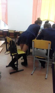 College Girl in a Skirt And Knee-High Boots Bending Over the Desk Classroom Photo