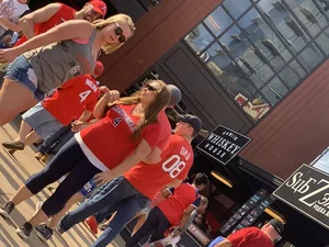 Bunch of girls in various outfits at a Cardinals baseball game