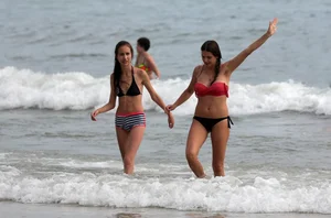 Skinny small boobed girl in a bikini on the beach with her friend