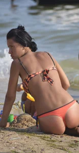 Orange thong bikini brunette sexy on the beach and showing some camel toe