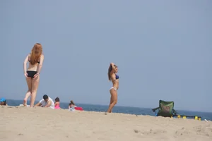 Redhead and brunette friends looking sexy in bikinis on the beach