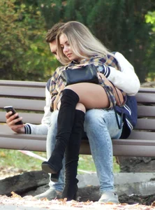 Girl in High-Heeled Go-Go Boots and Pantyhose Sitting on Her Boyfriend's Lap Cross-Legged in a Park - Hot Skinny Legs Candid