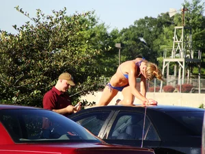 Group of cute girls at a car wash in bikinis and shorts