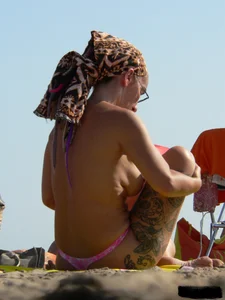 Topless tattooed lady at the beach with a nice ass in pink thong bikini