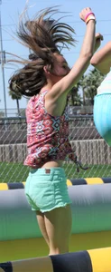 Brunette skinny teen in green shorts playing in a bounce house