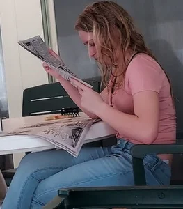Girl with wet hair wearing jeans reading a newspaper