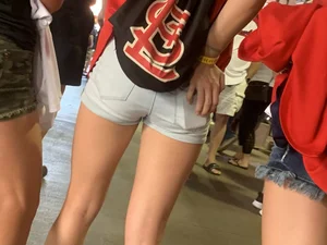 Bunch of girls in various outfits at a Cardinals baseball game