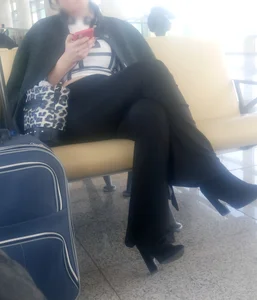 Girl in Pants And High-Heeled Shoes Sitting at the Station With Crossed Legs