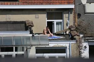 Neighbor on rooftop tanning in bikinis