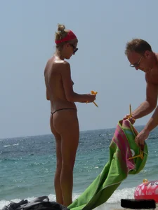 Topless skinny blonde lady in a g-string bikini at the beach