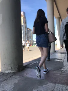Cute Girl in a Short Denim Skirt Walking on a Street And Waiting on a Crosswalk Gallery