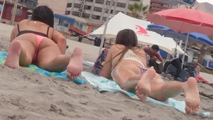 Pink and patterned bikini girls' asses laying on the beach