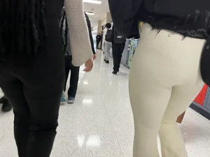 Two college teens wearing tight pants walking down the hallway