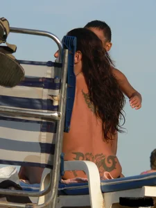 Topless tattooed lady on the beach with fake big tits