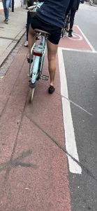 Girl on a bike wearing pantyhose, skirt and flats standing with her shoe half taken off