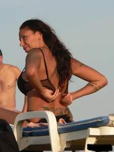 Topless tattooed lady on the beach with fake big tits