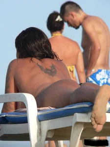Topless tattooed lady on the beach with fake big tits
