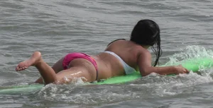 Brunette bikini girl on the beach and surfing in her bikini