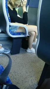 Young candid girl wearing shorts sitting with crossed legs in a public train creepshot