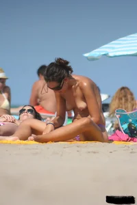 2 topless girls at the beach in thongs