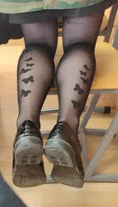 Closeup Photo of a College Teen's Legs in Black Pantyhose With a Cute Butterflies Pattern, Standing on Her Knees on a Chair in Class