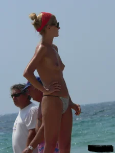 Topless skinny blonde lady in a g-string bikini at the beach