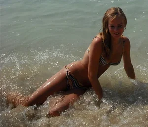 Very skinny girl sitting in water at the beach