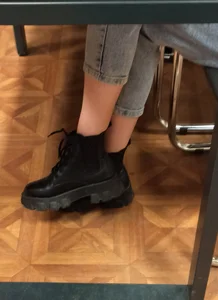 Candid college teen's crossed legs closeup in tight jeans and boots in class