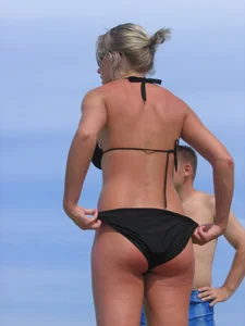 Cute blonde on the beach in a black bikini with nice boobs