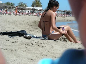Brunette looking sexy on the beach in a blue thong bikini