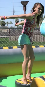 Brunette skinny teen in green shorts playing in a bounce house