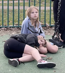 Cute scene with two candid teens on the ground, one resting her head on another's lap