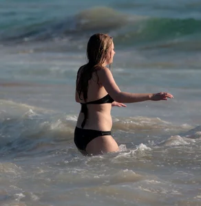 Cute bikini girl in the water in a black bikini