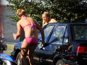 Group of cute girls at a car wash in bikinis and shorts