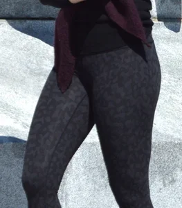 Brunette with glasses on the phone in tight patterned leggings