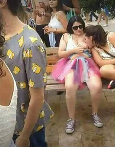 One girl publicly breastfeeding another girl, which is completely normal and not strange at all