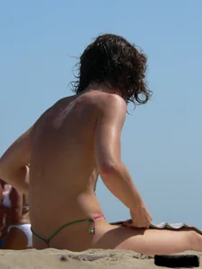 Topless beach milf looking sexy in a tiny g-string bikini