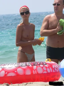 Topless skinny blonde lady in a g-string bikini at the beach