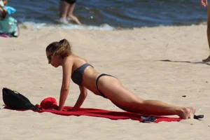 Hottie undressing from her red shorts to her bikini to layout on the beach