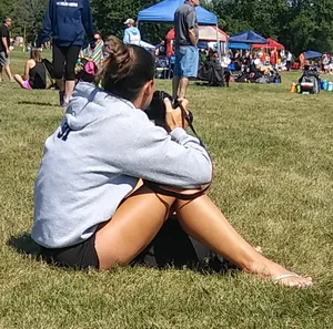 Candid Photographer Girl in Shorts and Sandals Sitting on the Grass in a Park
