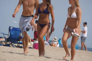 Two sexy friends, one blonde and one brunette, on the beach in bikinis