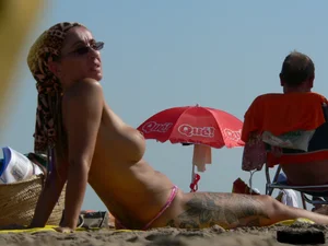 Topless tattooed lady at the beach with a nice ass in pink thong bikini