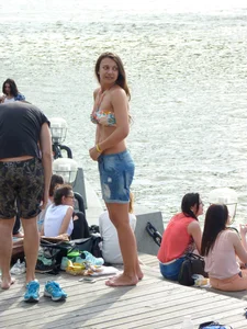 Cute Girl in Denim Shorts and Swimsuit Undressing on the Riverbank Candid Photo
