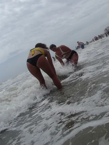 Beach babe in yellow and black bikini bending over