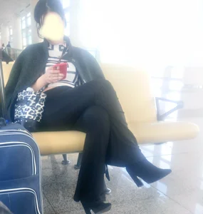Girl in Pants And High-Heeled Shoes Sitting With Crossed Legs at the Station